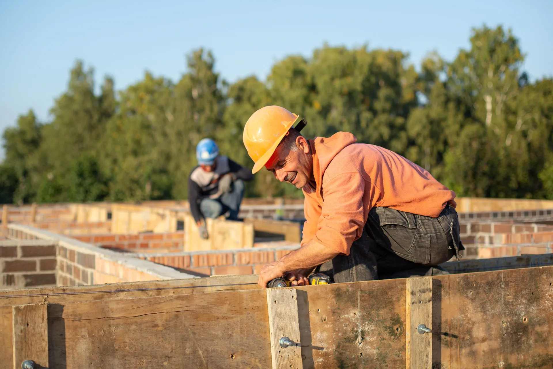Site supervisor reviewing worker compliance status on a tablet at a construction site entrance