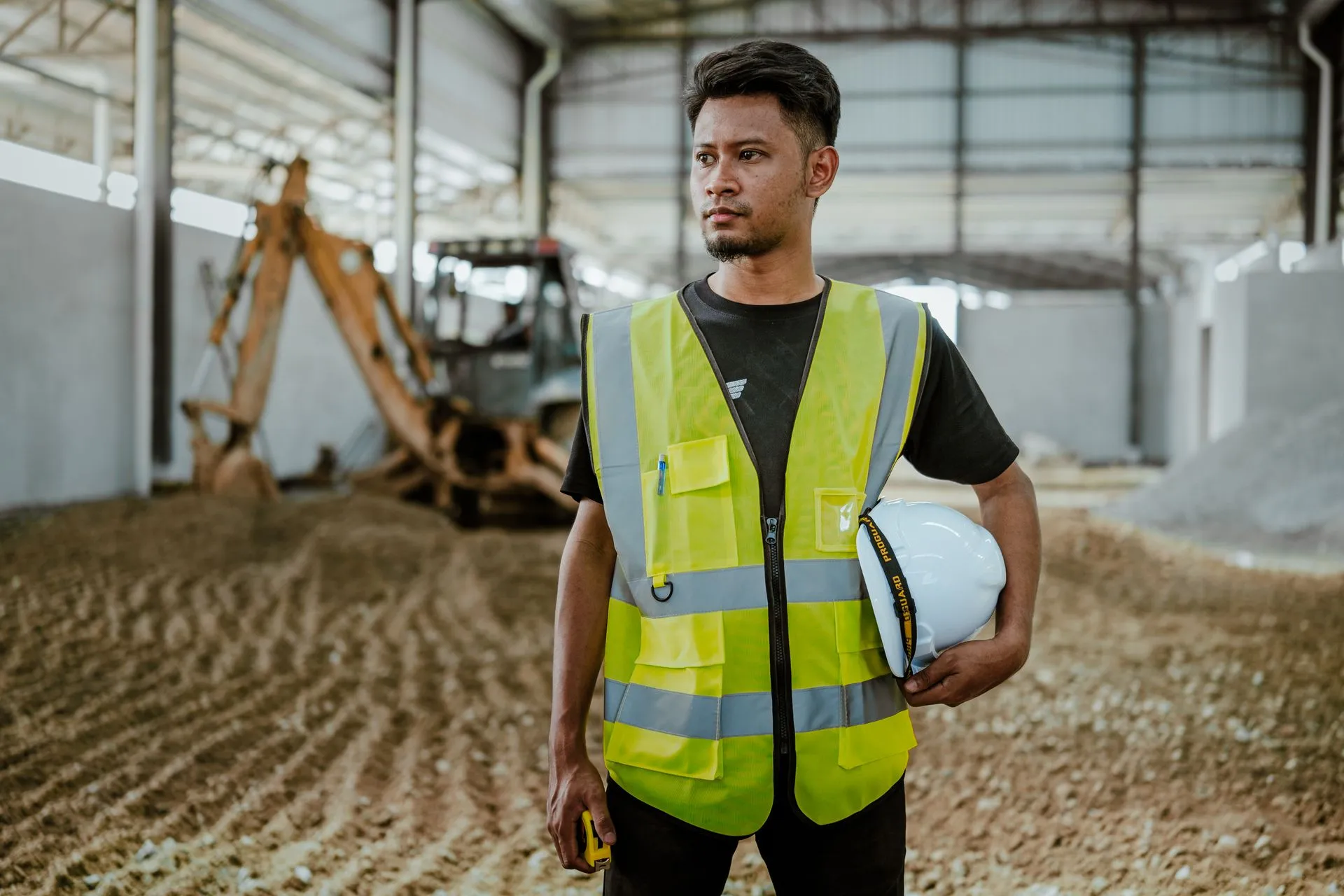 Construction worker in high-visibility clothing and hard hat on an active building site